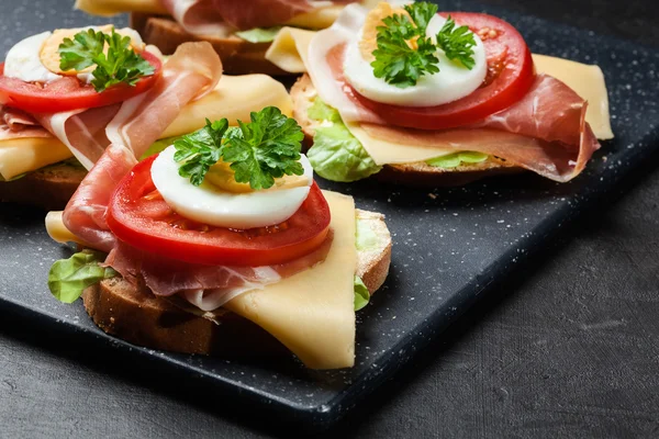 Delicioso sándwich con jamón de jamón, queso, tomate y huevo — Foto de Stock