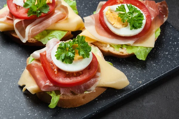 Heerlijke sandwich met prosciutto-ham, kaas, tomaat en ei — Stockfoto