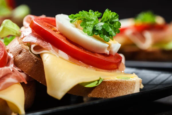 Delicious sandwich with prosciutto ham, cheese, tomato and egg — Stock Photo, Image