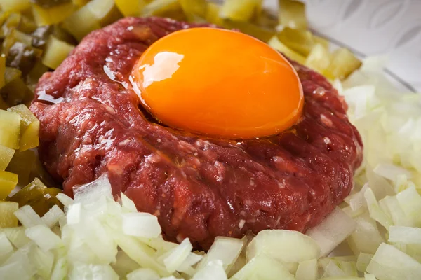 Steak tartare with egg yolk, onions and pickles — Stock Photo, Image