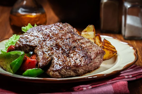 Porções de bife grelhado com batatas grelhadas e páprica — Fotografia de Stock