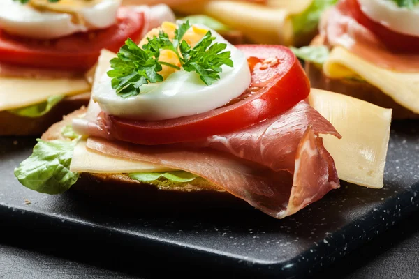 Prosciutto jambonu, peynir, domates ve yumurta ile lezzetli sandviç — Stok fotoğraf