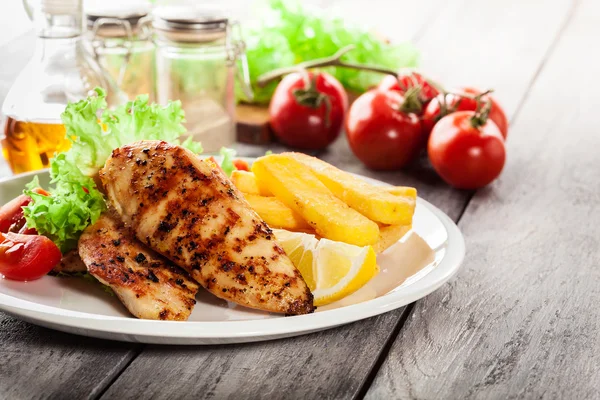 Petti di pollo alla griglia serviti con patatine fritte e insalata fresca — Foto Stock