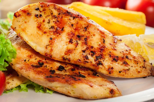 Grilled chicken breasts served with fries and fresh salad — Stock Photo, Image