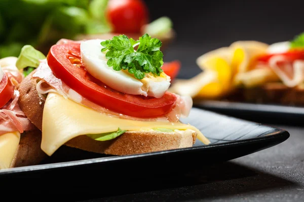 Delicious sandwich with prosciutto ham, cheese, tomato and egg — Stock Photo, Image