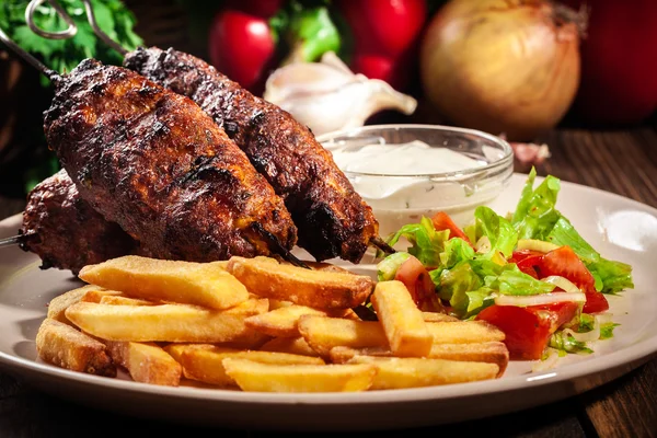 Grilled shish kebab served with fried chips and salad — Stock Photo, Image