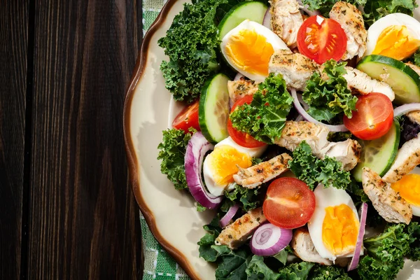 Frischer Salat mit Huhn, Tomaten, Eiern und Salat auf Teller — Stockfoto