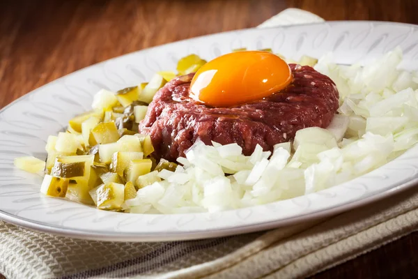 Steak tartare with egg yolk, onions and pickles — Stock Photo, Image