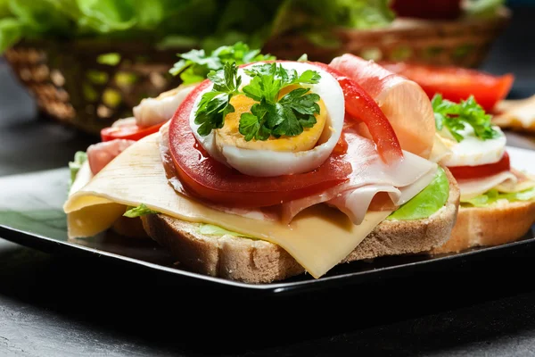 Finom szendvics sonka, sajt, paradicsom és a tojás — Stock Fotó