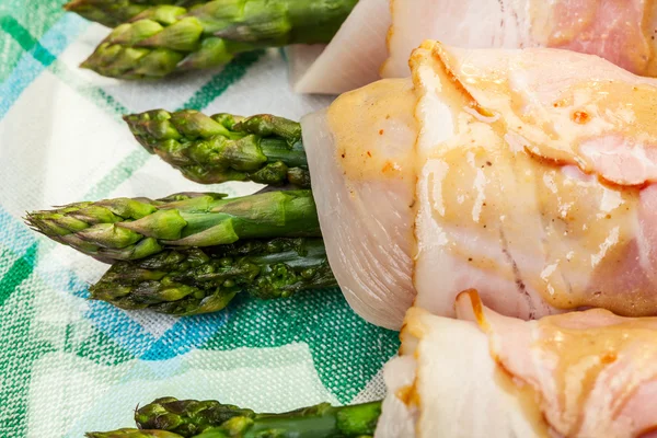 Asparagus wrapped in chicken and bacon in a baking dish