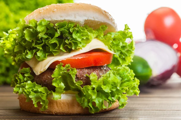 Cheeseburger met sla, uien en tomaten in een broodje sesam — Stockfoto