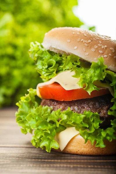 Cheeseburger met sla, uien en tomaten in een broodje sesam — Stockfoto