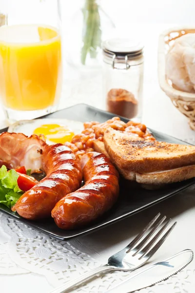 Englisches Frühstück mit Speck, Wurst, Ei, gebackenen Bohnen und — Stockfoto