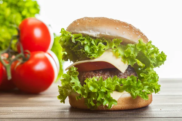 Hambúrguer de queijo com alface, cebola e tomate em um pão de gergelim — Fotografia de Stock