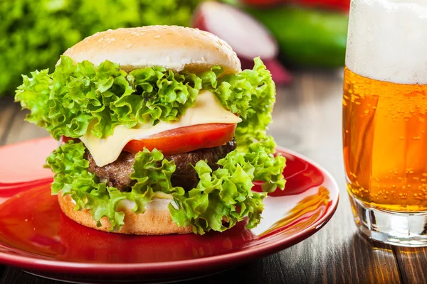 Hambúrguer de queijo em um prato com cerveja — Fotografia de Stock