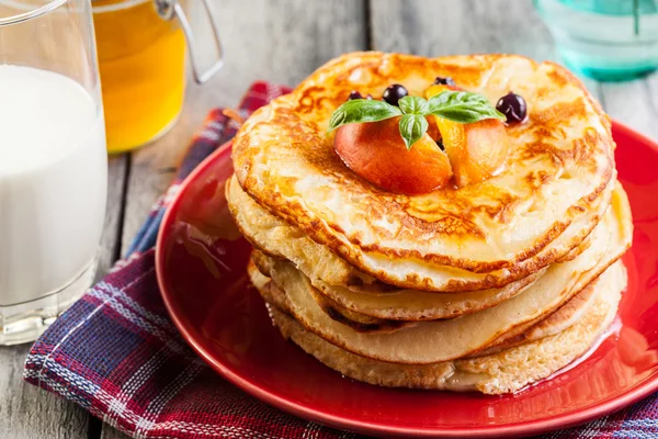 Pancakes with honey, fruit and glass of milk — Stock Photo, Image