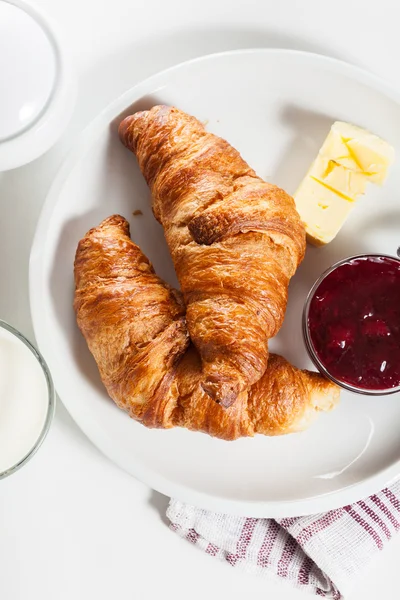 Croissants au beurre et un verre de lait dans une assiette — Photo