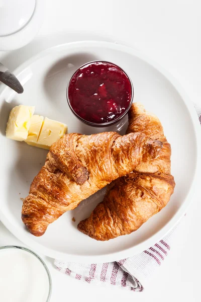 Croissants with butter and a glass of milk on a plate — Stock Photo, Image