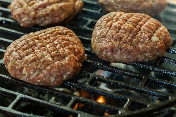 Hambúrgueres crus na churrasqueira com fogo — Fotografia de Stock