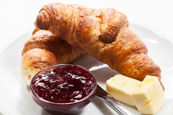 Croissants au beurre et un verre de lait dans une assiette — Photo