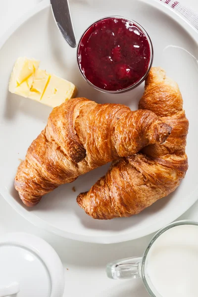 Croissants with butter and a glass of milk on a plate — Stock Photo, Image