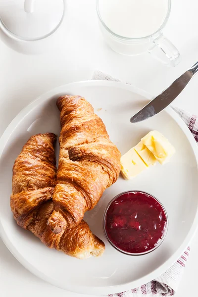 Croissants with butter and a glass of milk on a plate — Stock Photo, Image