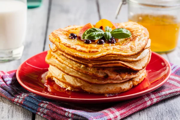 Pancakes with honey, fruit and glass of milk — Stock Photo, Image