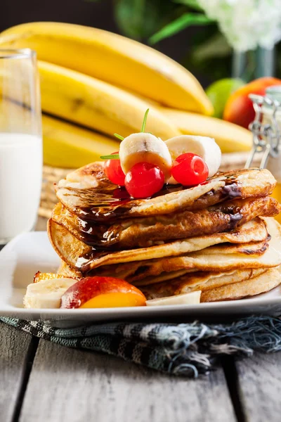 Pancakes with chocolate sauce fruit and glass of milk — Stock Photo, Image