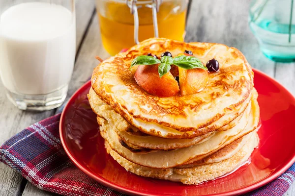 Pancakes with honey, fruit and glass of milk — Stock Photo, Image