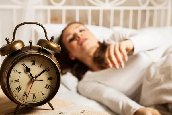 Mulher dormindo na cama ao lado do despertador — Fotografia de Stock