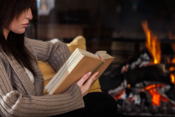 Frau liest ein Buch am Kamin — Stockfoto