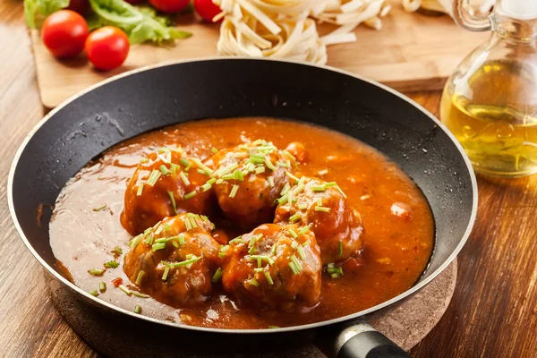 Meatballs with tomato sauce on black pan — Stock Photo, Image