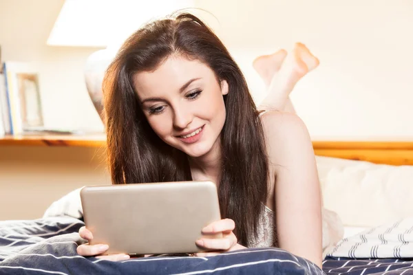 Женщина лежит на кровати и с помощью планшета — стоковое фото