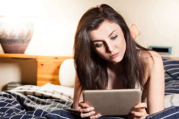 Mujer acostada en la cama y usando tableta — Foto de Stock