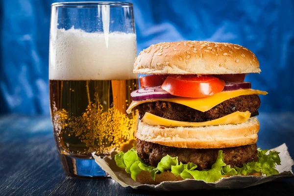 Hamburger on paper with beer — Stock Photo, Image