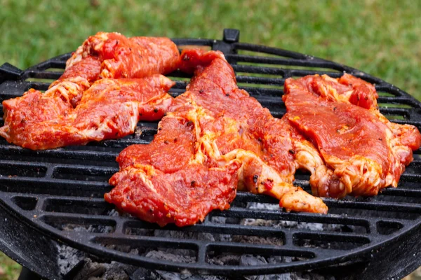 Grilling pork steaks on barbecue grill — Stock Photo, Image