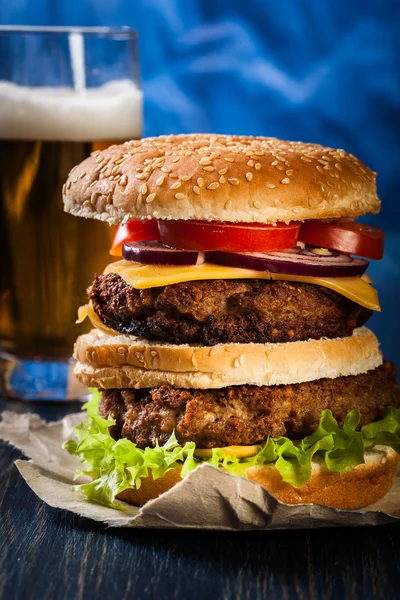 Hamburger on paper with beer — Stock Photo, Image