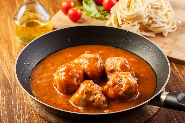 Meatballs with tomato sauce on black pan — Stock Photo, Image
