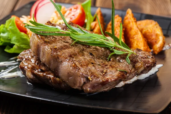 Porção de bife de vaca servido com batatas assadas — Fotografia de Stock