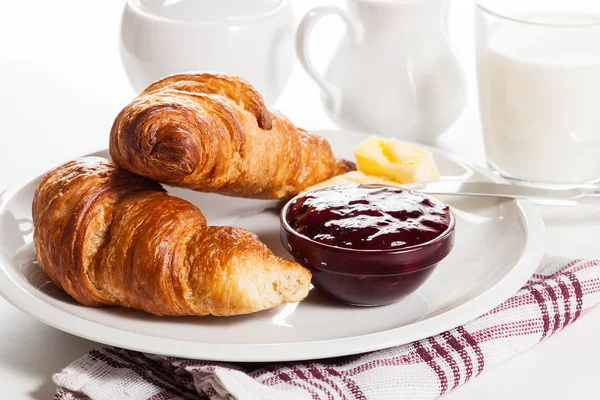 Croissants frescos con mantequilla y un vaso de leche —  Fotos de Stock