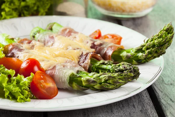 Baked green asparagus with prosciutto and cheese — Stock Photo, Image