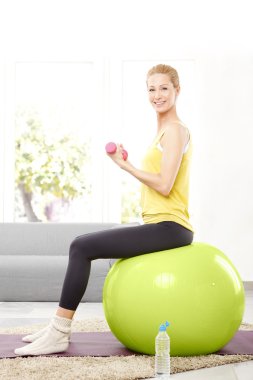 Kadın dambıllarla çalışıyor.