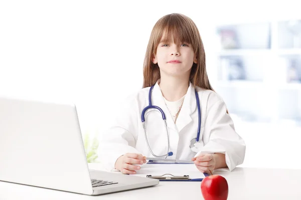 Chica vestida con traje de médico mientras trabajaba detrás de la computadora portátil —  Fotos de Stock