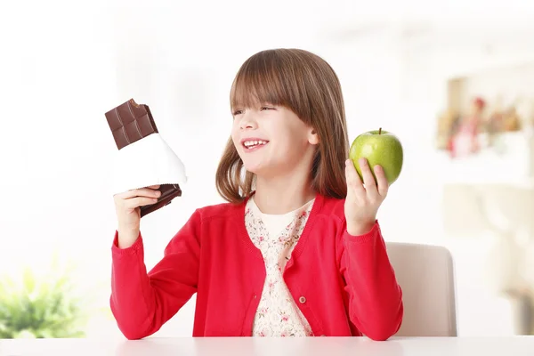 Девушка держит шоколад или яблоко — стоковое фото