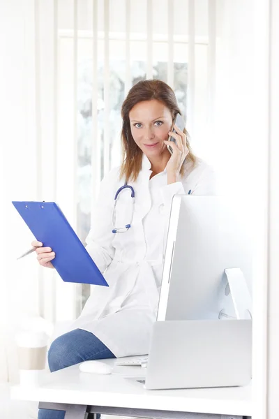 Médico segurando prancheta e fazendo chamada — Fotografia de Stock