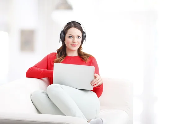 G vrouw met behulp van haar laptop en hoofdtelefoon — Stockfoto