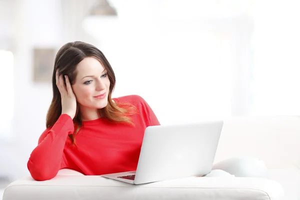 Mulher usando laptop enquanto relaxa em casa . — Fotografia de Stock