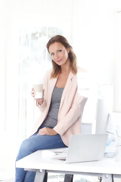 Affärskvinna sitter vid skrivbord och dricka — Stockfoto