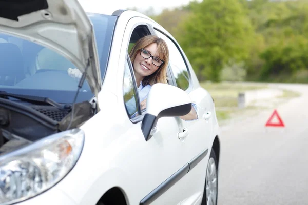 Woman sitting at her broken down car — Stockfoto