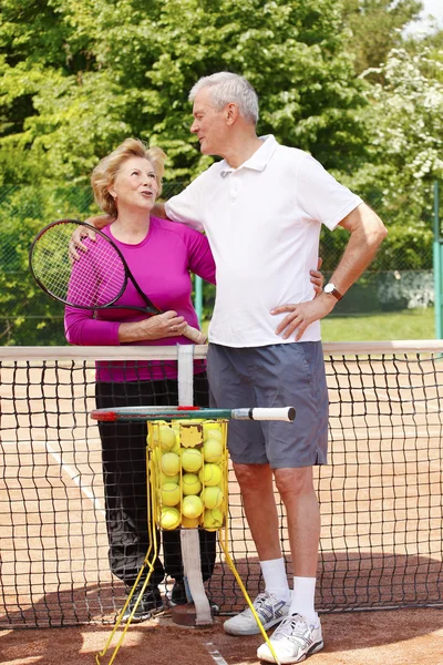 Pareja de ancianos de pie en la cancha de tenis — Foto de Stock